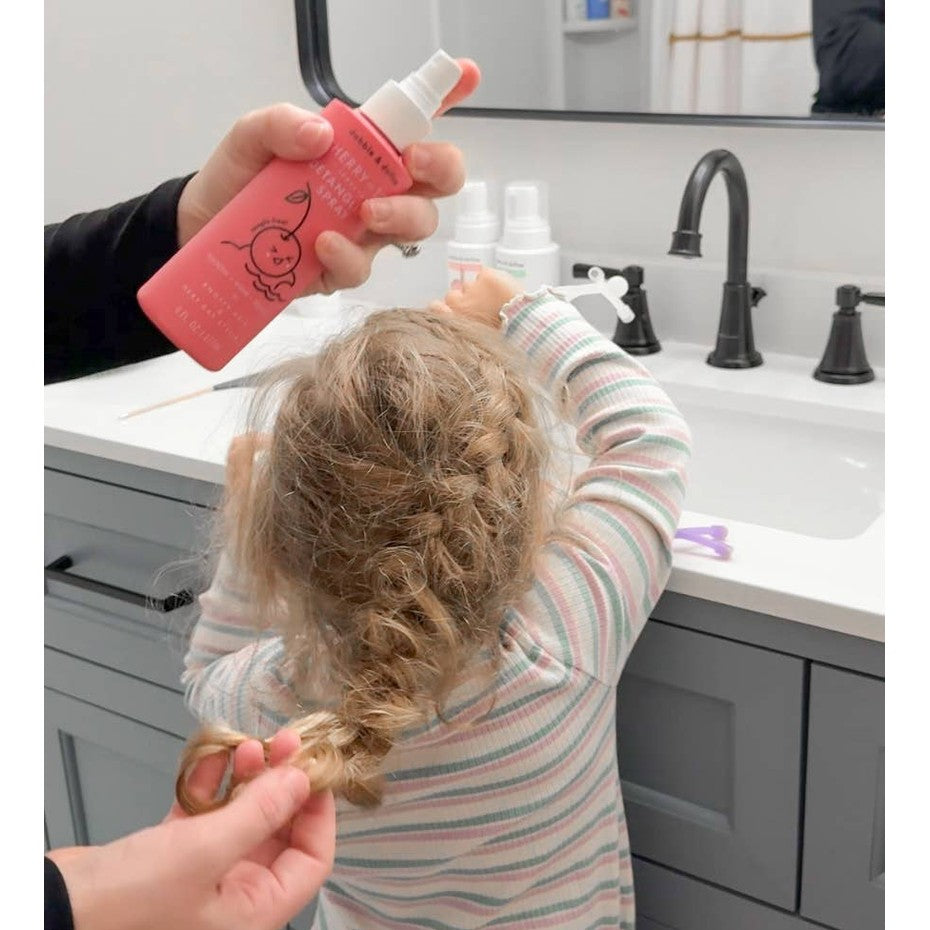Dabble & Dollop Hair Detangling & Conditioning Spray Cherry on Top being spritzed onto a child's tangled hair in a bathroom.