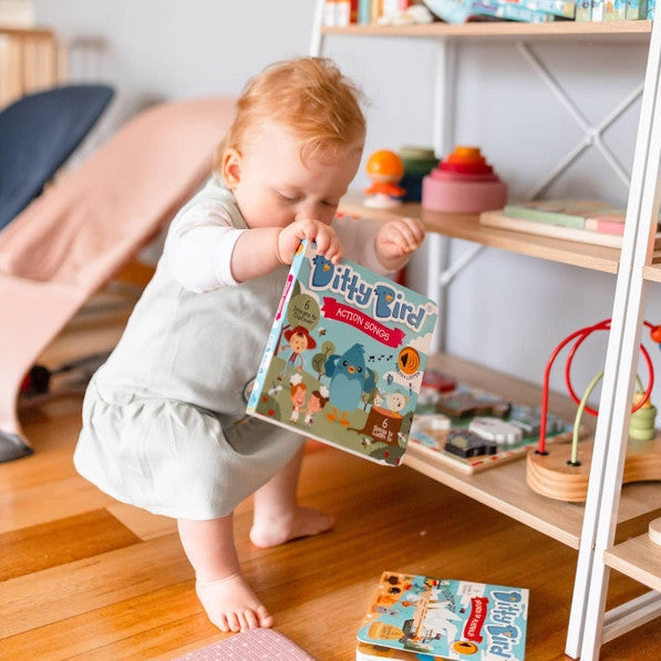Ditty Bird Sound Book Action Songs USB-C Rechargeable held by a toddler in a bright playroom