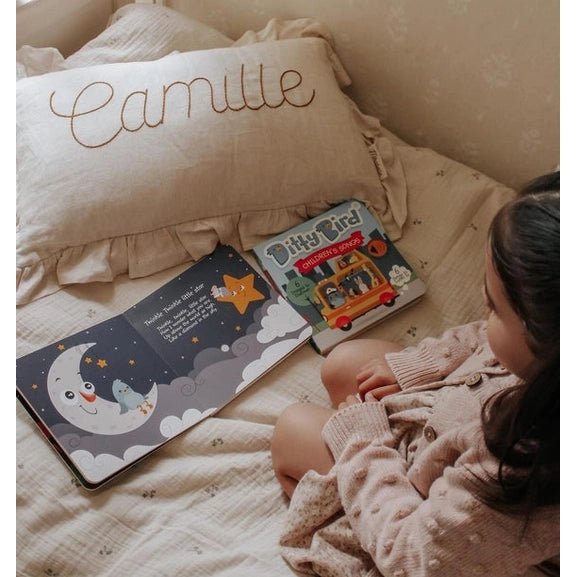 Ditty Bird Sound Book Bedtime Songs USB-C Rechargeable opened on a cozy bed as a child reads.
