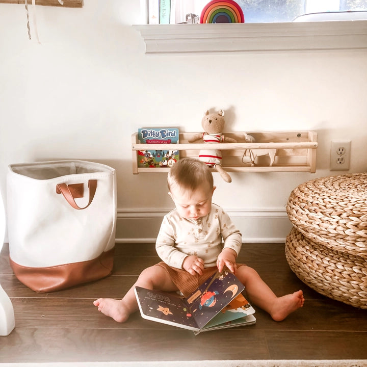 Ditty Bird Sound Book Bedtime Songs by DITTY BIRD; a baby sits on a wooden floor flipping through the open book.