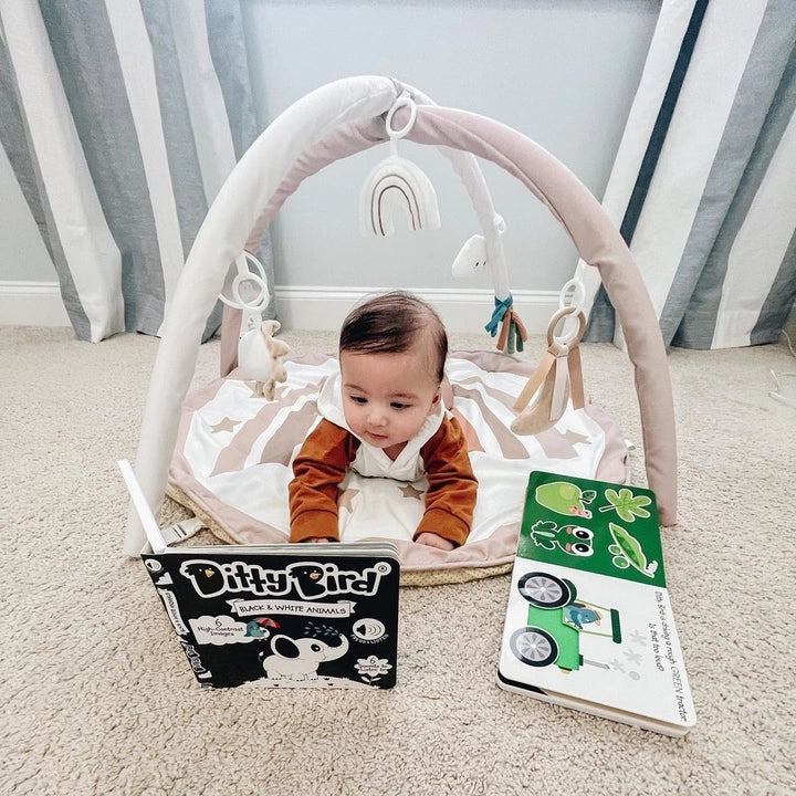 Ditty Bird Sound Book Black and White Animals USB-C Rechargeable; baby sits on a soft mat, looking at the book.
