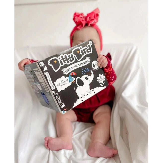 Ditty Bird Sound Book Black and White Animals USB-C Rechargeable held up by a baby on a white couch
