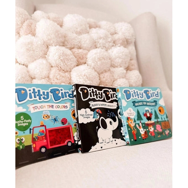 Ditty Bird Sound Book Black and White Animals USB-C Rechargeable; three colorful books shown beside a fluffy cream pom-pom blanket.