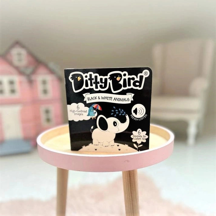 Ditty Bird Sound Book Black & White Animals USB-C Rechargeable on a pink round table, high-contrast cover.
