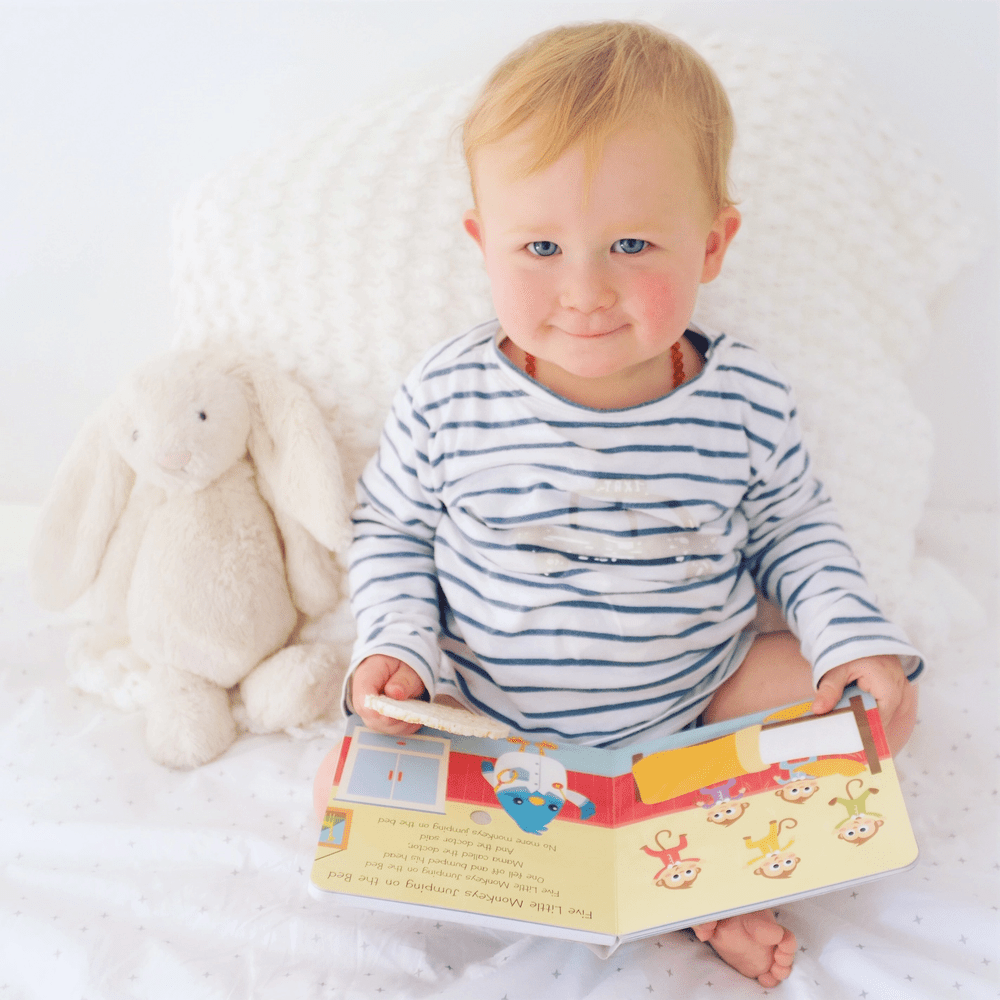 Ditty Bird Sound Book USB-C Rechargeable read by a smiling toddler in a striped shirt beside a plush bunny.