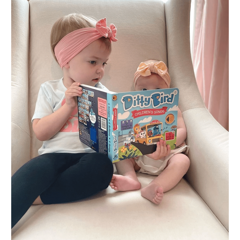Ditty Bird Sound Book Children's Songs USB-C Rechargeable read by two babies on a cream sofa.