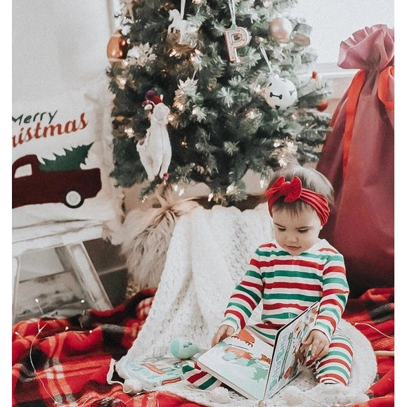 Ditty Bird Sound Book Christmas Songs USB-C Rechargeable; toddler in striped pajamas reads beside a decorated Christmas tree.