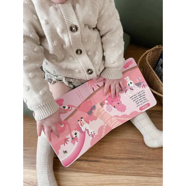 Ditty Bird Sound Book Color Songs USB-C Rechargeable, pink kids' book; child taps and holds it on a wood floor.