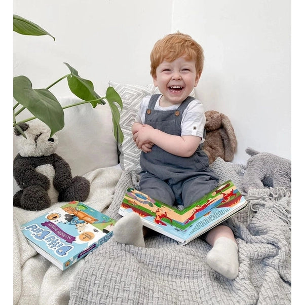 Ditty Bird Sound Book Dinosaur Sounds USB-C Rechargeable; smiling toddler reads the open book among plush toys.