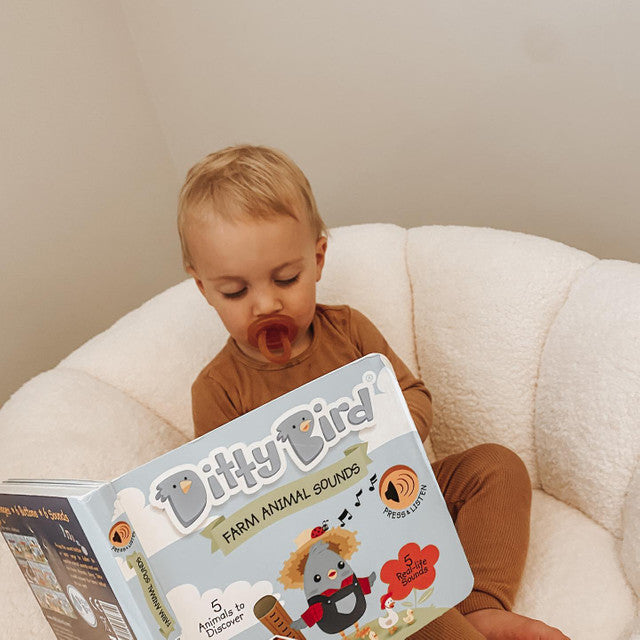 Ditty Bird Sound Book Farm Animal USB-C Rechargeable, baby in brown onesie sits in a cream chair exploring sounds