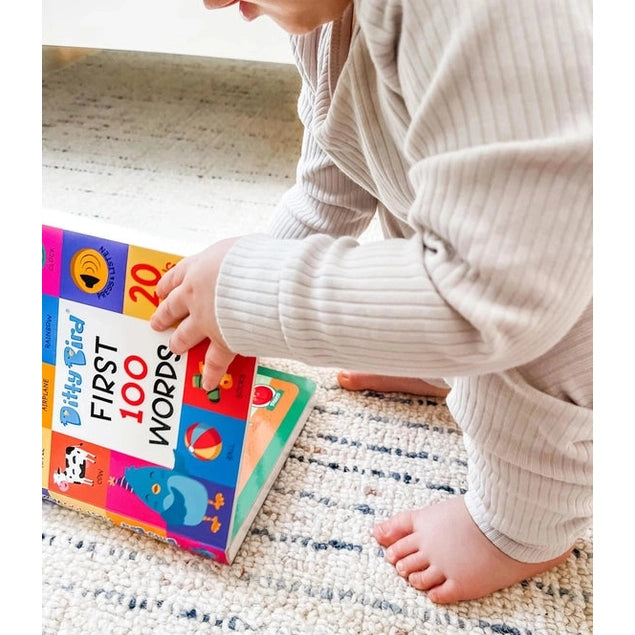 Ditty Bird Sound Book First 100 Words USB-C Rechargeable; toddler taps colorful pages on a rug.