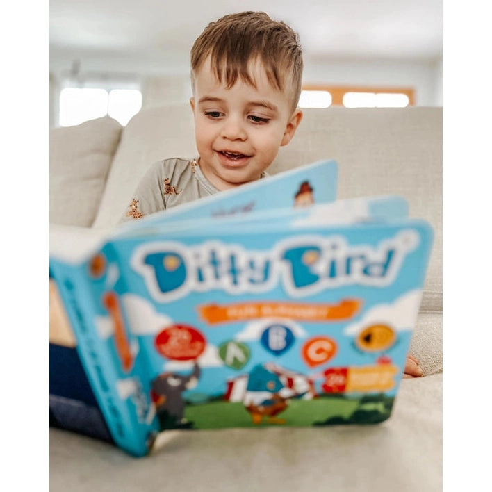 Ditty Bird Sound Book Fun Alphabet USB-C Rechargeable being read by a smiling toddler on a couch.