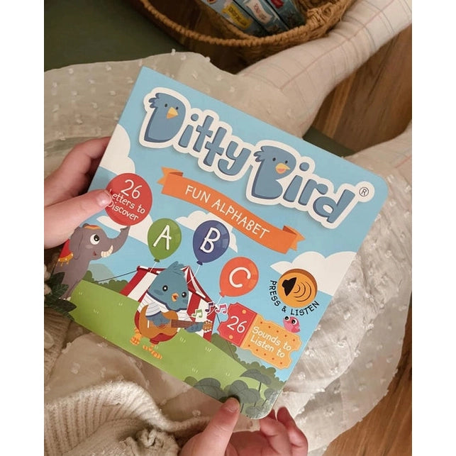 Ditty Bird Sound Book Fun Alphabet USB-C Rechargeable held by a child on a cozy blanket; colorful ABC icons visible.