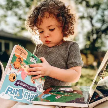 Ditty Bird Sound Book Music to Dance To USB-C Rechargeable being read by a curious toddler outdoors