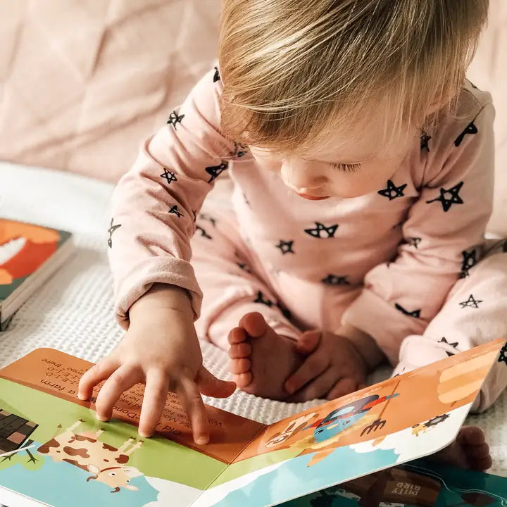 Ditty Bird Sound Book Nursery Rhymes USB-C rechargeable; toddler taps colorful pages while sitting on a quilt.