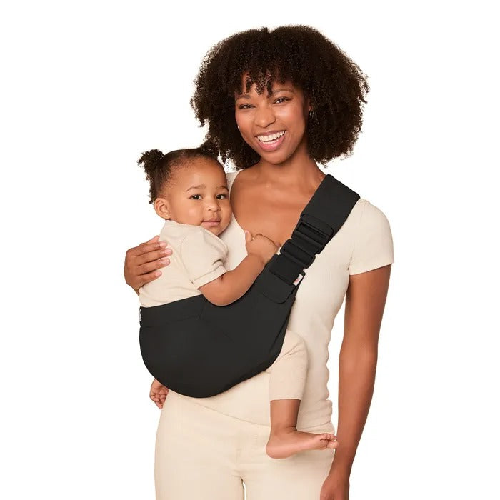 ERGOBABY Upsie Sling Carrier in black worn by smiling mom with baby securely snuggled against her chest.