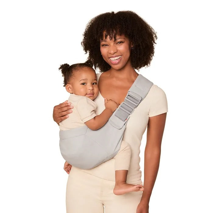 ERGOBABY Upsie Sling Carrier in light gray; mom securely carries baby on her chest in the ergonomic one-shoulder sling.