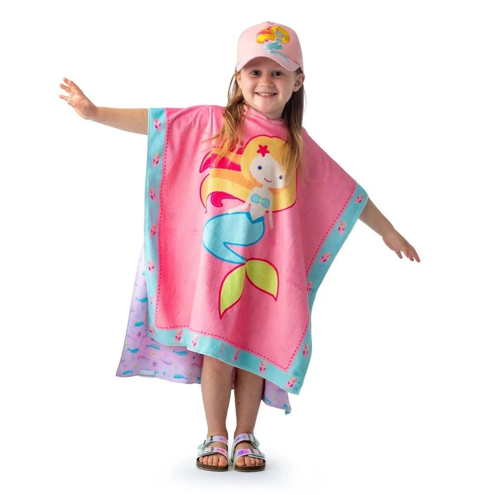 Flapjackkids Cover Up Mermaid/Narwhal pink poncho worn by a smiling girl with arms outstretched, aqua trim, mermaid design.