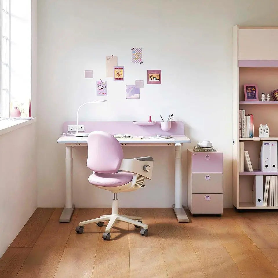 Iloom Linki Plus Motion Desk in pastel pink with white frame, shown with a pink ergonomic chair in a bright, tidy study