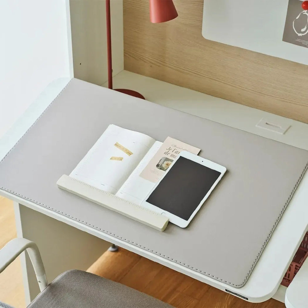 Iloom Linki Plus desk pad in gray with stitched edges on white desk, with notebook and tablet nearby.