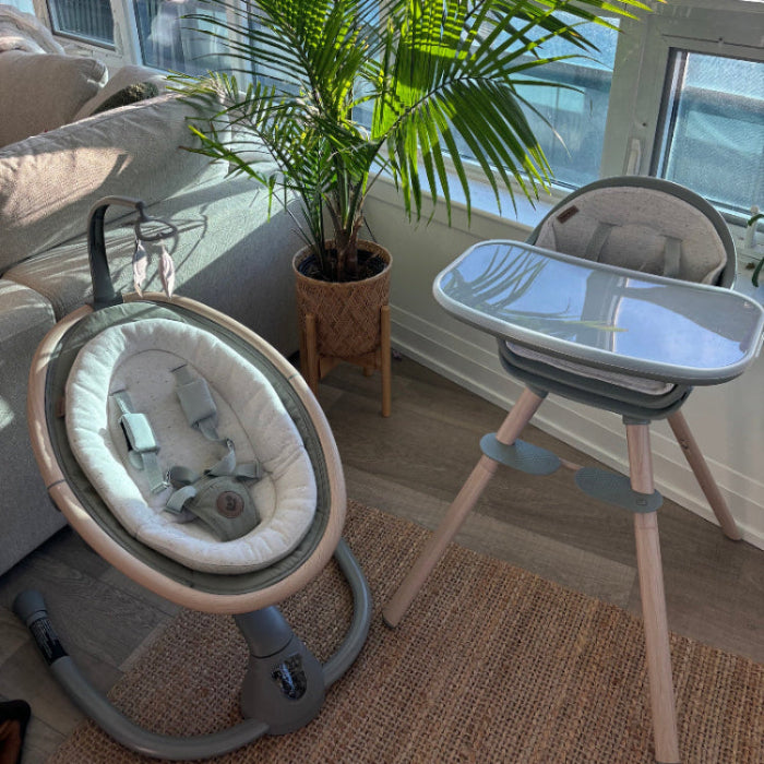 MAXI COSI Cassia Swing baby seat on gray stand with plush white lining in a sunlit room