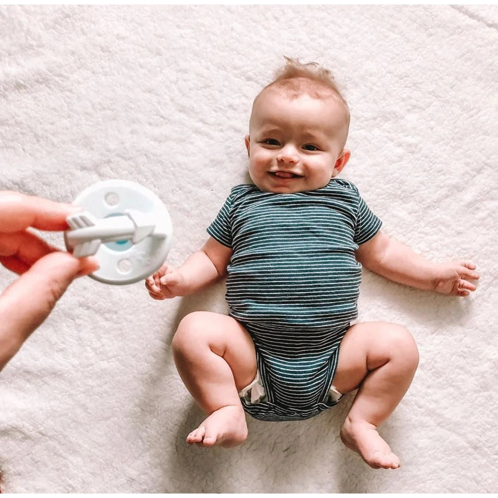 Itzy Ritzy Sweetie Soother pacifier set, 2-pack for 0M+, baby in striped teal onesie.