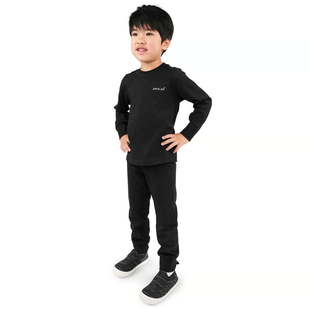 Young child in JAN & JUL Kids Cotton Blend Base Layer Tops Black set, posing with hands on hips in a cozy all-black outfit.