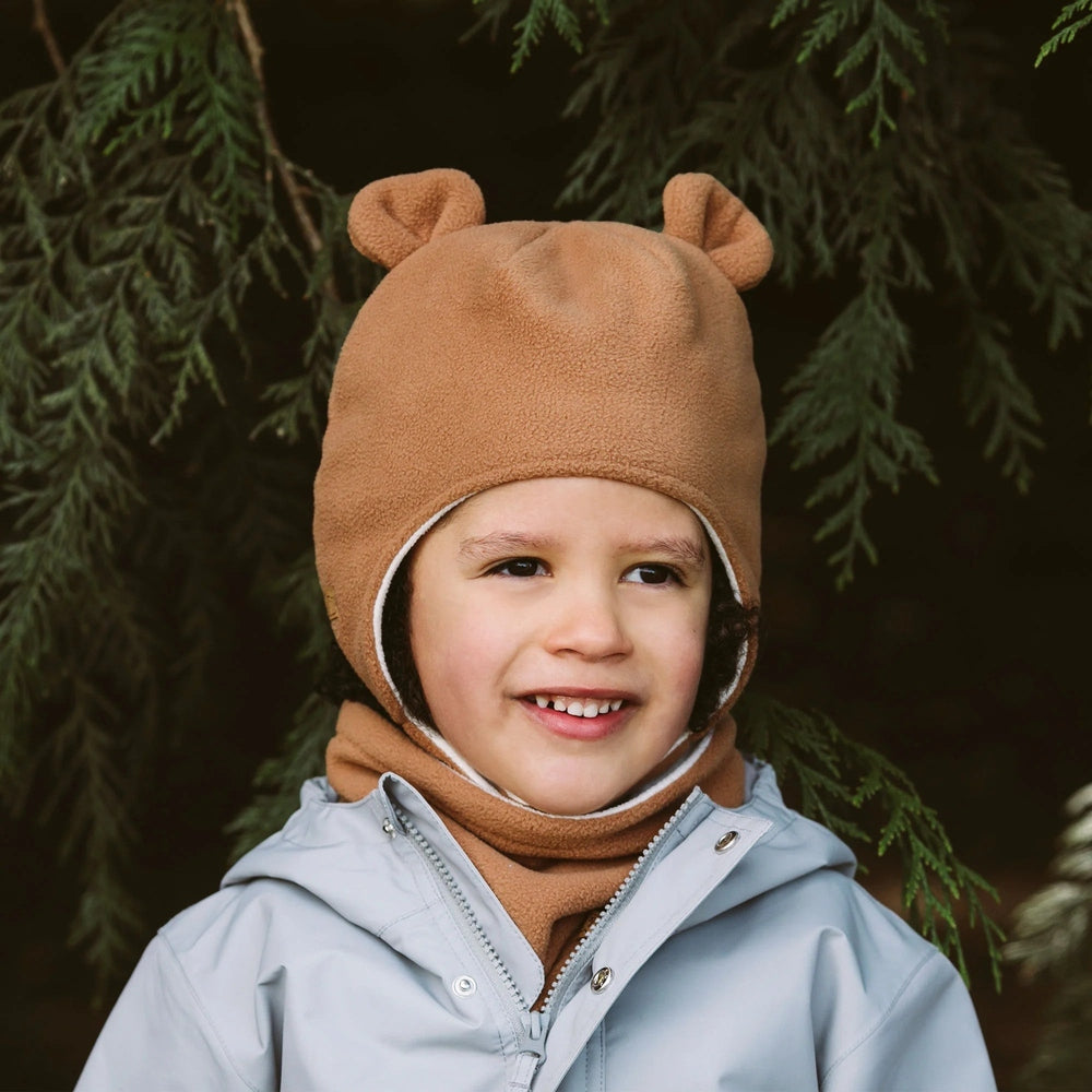 JAN & JUL Kids Fleece Brown Bear Hat with Ears on a smiling toddler wearing a light jacket