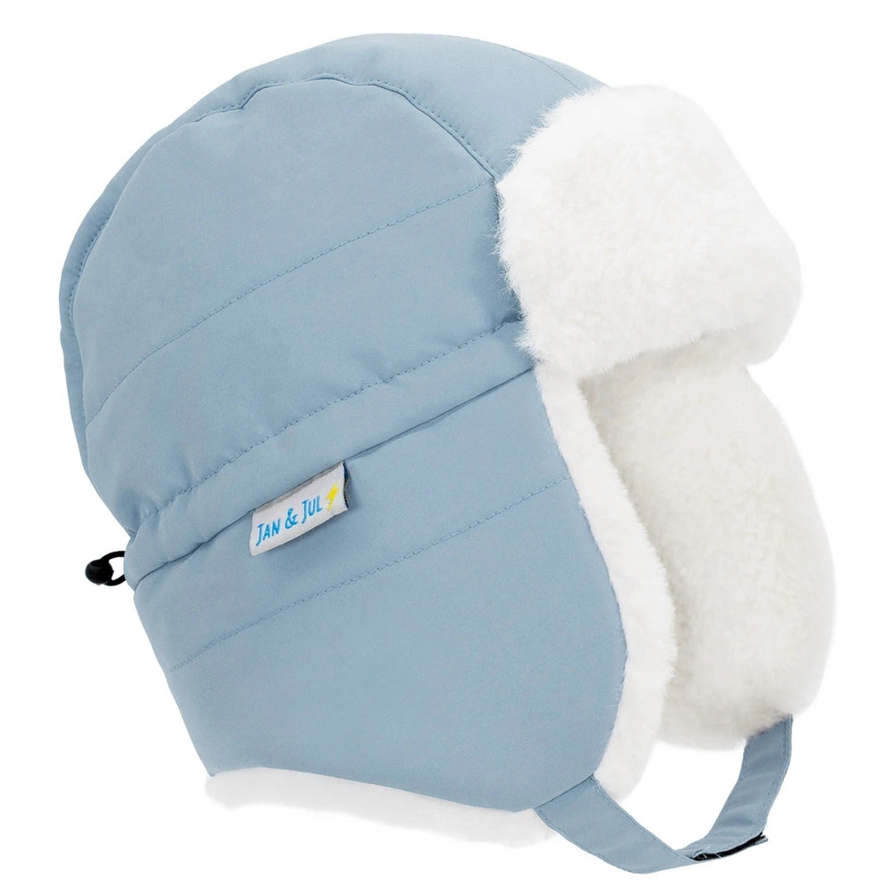 Jan & Jul Kids Insulated Winter Hat in dusty blue with white faux fur lining; ear flaps secured for warmth.