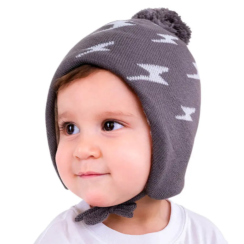 Jan & Jul Kids Knitted Beanie Hat in grey with lightning bolt pattern, pom-pom, and chin ties worn by toddler.