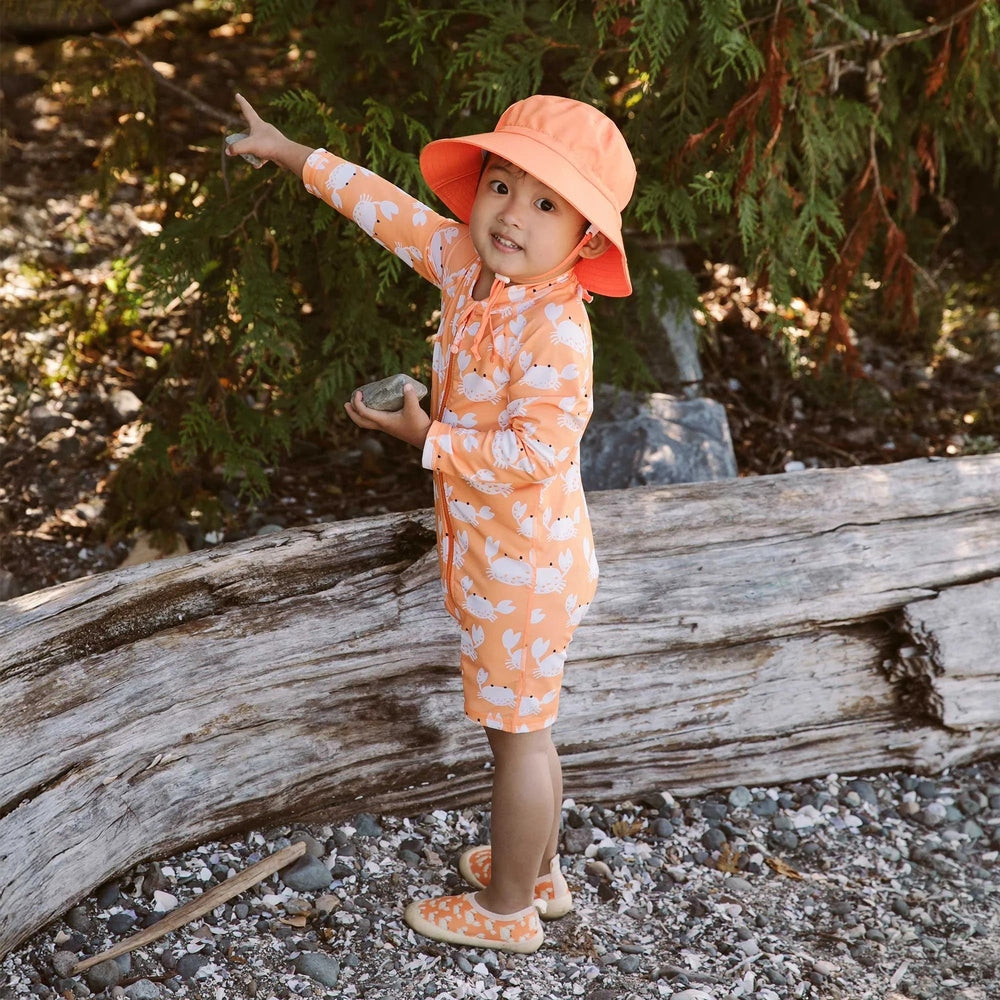 JAN & JUL Kids One-Piece UV Sun Suit Crabby Crab in orange; child points outdoors, wearing matching hat.