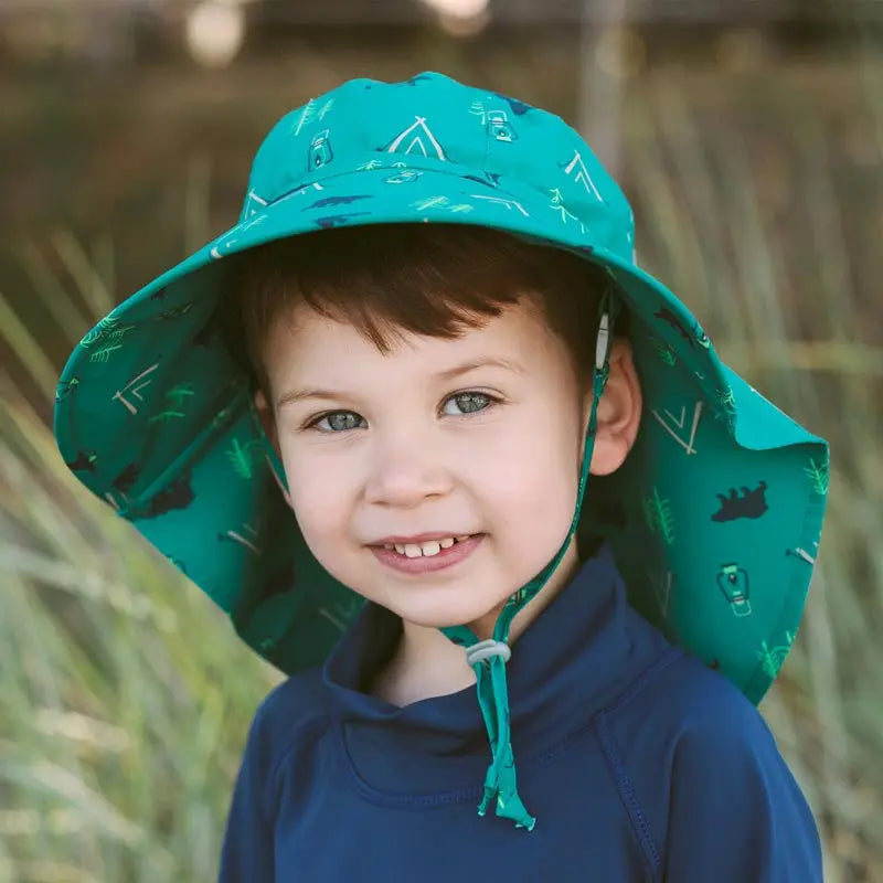 Jan & Jul Kids Water Repellent Adventure Hat in teal; child outdoors with chin strap secured.