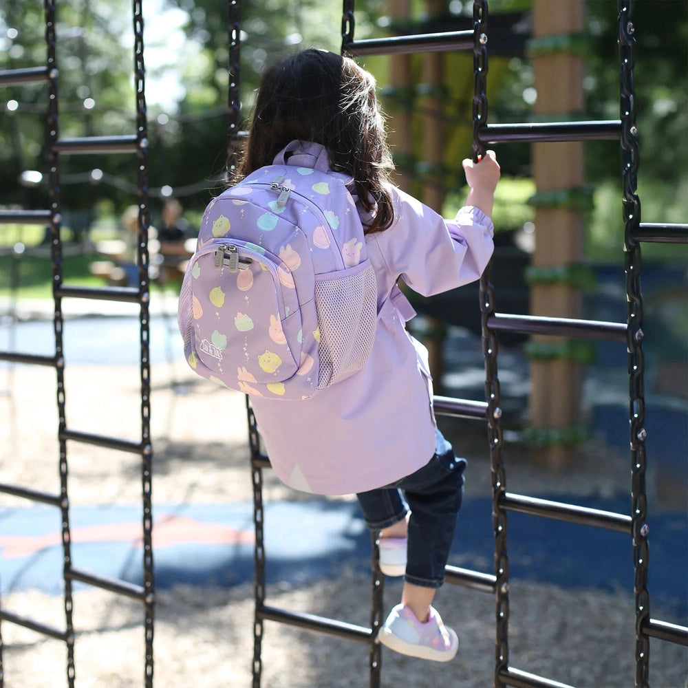 Jan & Jul Kids Mini Backpack lavender with pastel animal prints; child climbs a jungle gym, showing the side mesh pocket.