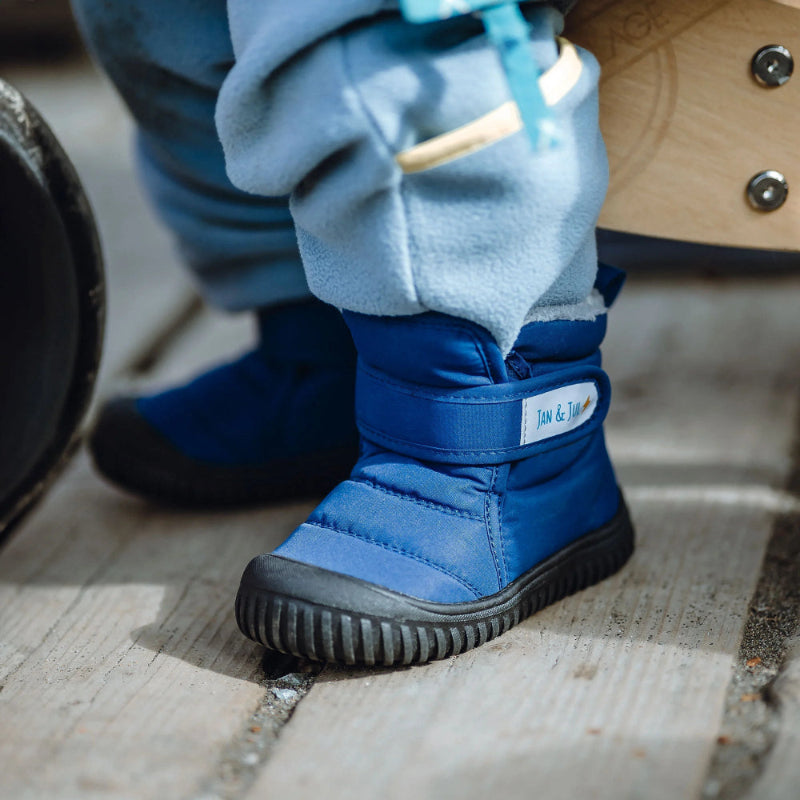 Jan & Jul Toasty Dry Booties Navy Forest; blue insulated baby boots with Velcro straps worn by a toddler standing on concrete.