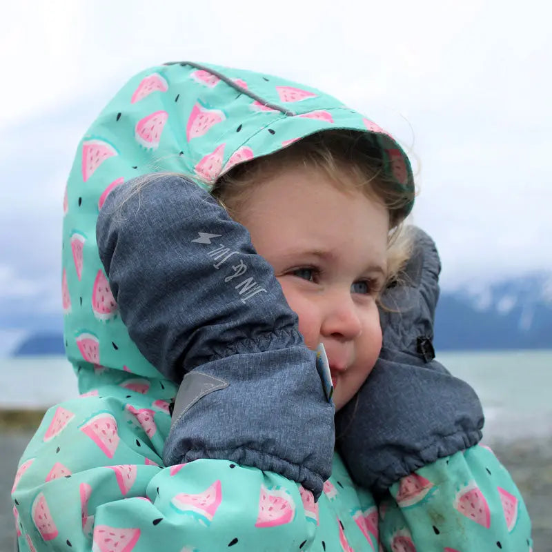 Jan & Jul Water-Resistant Cozy Dry Rain Mittens in blue-gray on a child, who cups cheeks to stay warm outdoors.