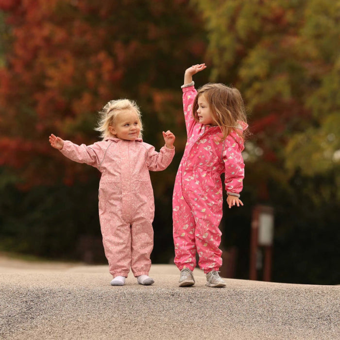 JAN & JUL Waterproof Cozy Dry Rain Suit Prairie Flowers; two toddlers in pink floral rain suits stand outdoors on a curb.