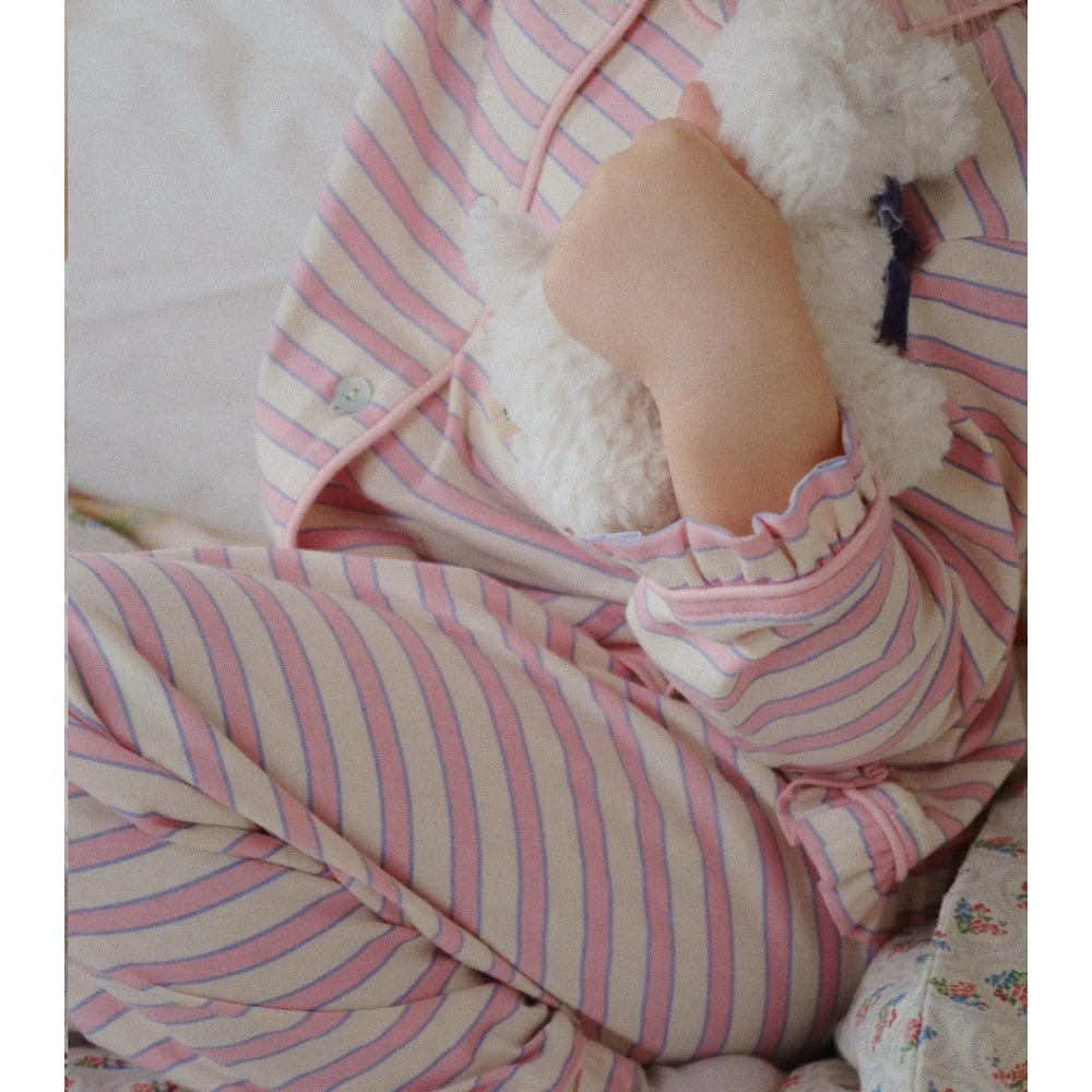 Konges Slojd Baby Animals plush being hugged by a child in pink striped pajamas, soft and comforting.