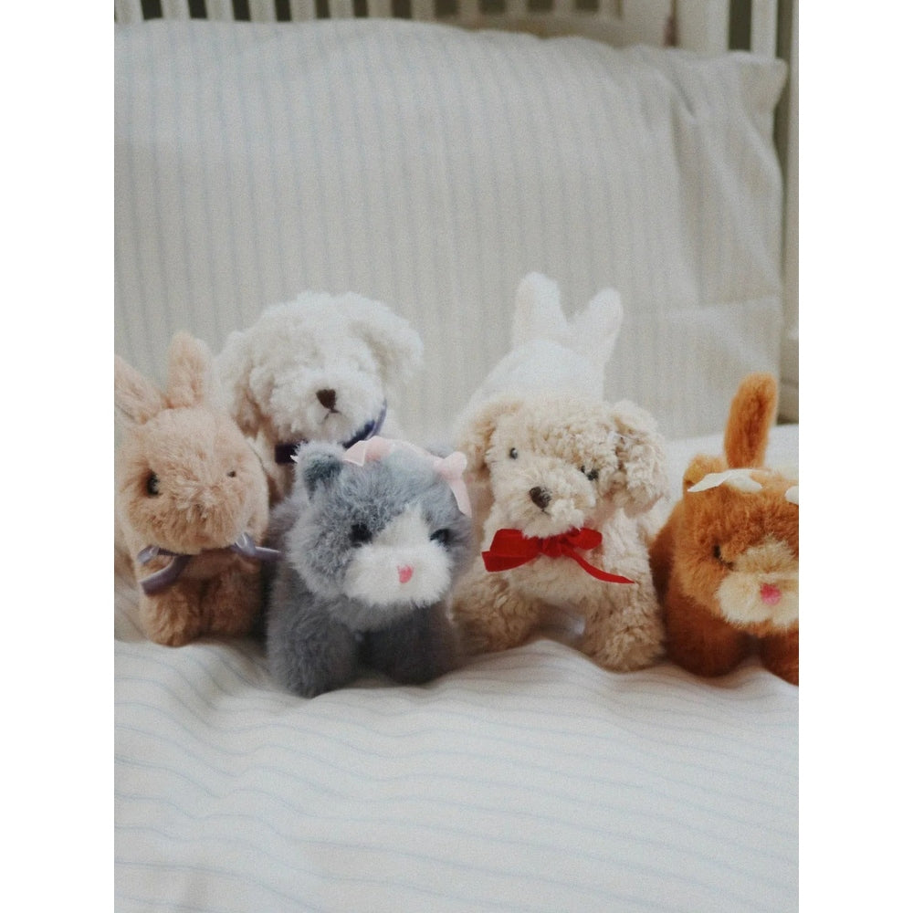 Konges Slojd Baby Animals plush toys set with softly colored bunnies and grey rabbit on a striped bed.