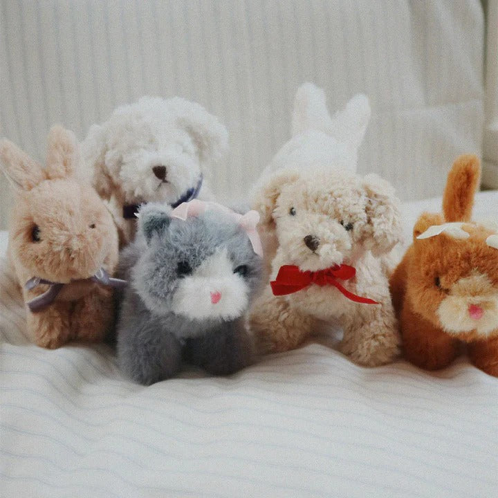 Konges Slojd Baby Animals plush toy set—five soft bunnies and cats with ribbons, lined up on a striped bed.