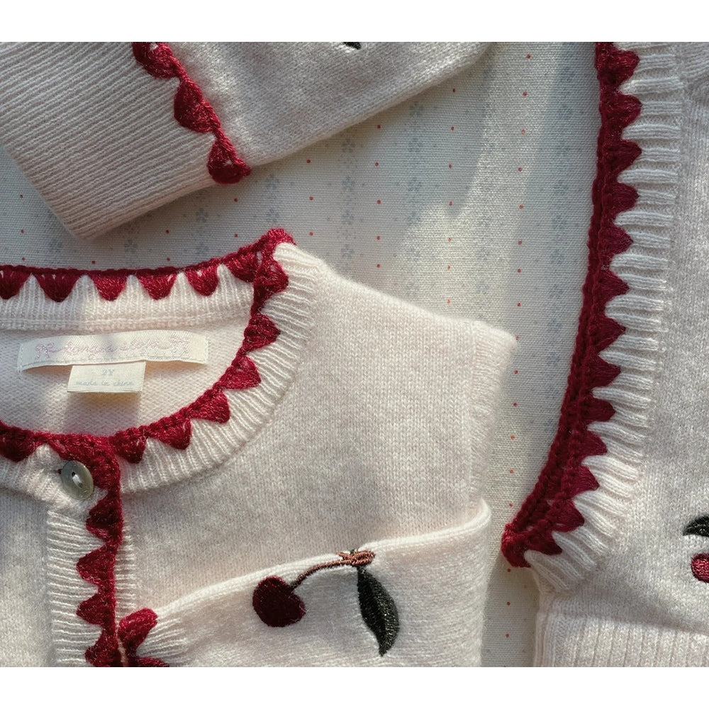 Konges Slojd Collette Cardigan Off White with red scalloped trim and cherry embroidery, laid flat to show trim and button placket.