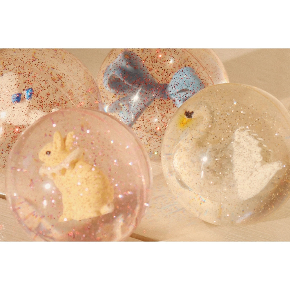 Konges Slojd Glitter Bouncing Ball Set Cherry/Swan: translucent glitter spheres with bunny and swan inside.