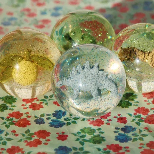 Konges Slojd Glitter Bouncing Ball Set Lemon/Tiger displayed as sparkling translucent spheres on a floral tablecloth.
