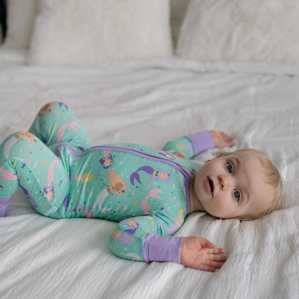 Littlesleepies Mermaid Magic Bamboo Viscose Zippy romper in mint green with purple cuffs, baby on her back proving the front zipper.