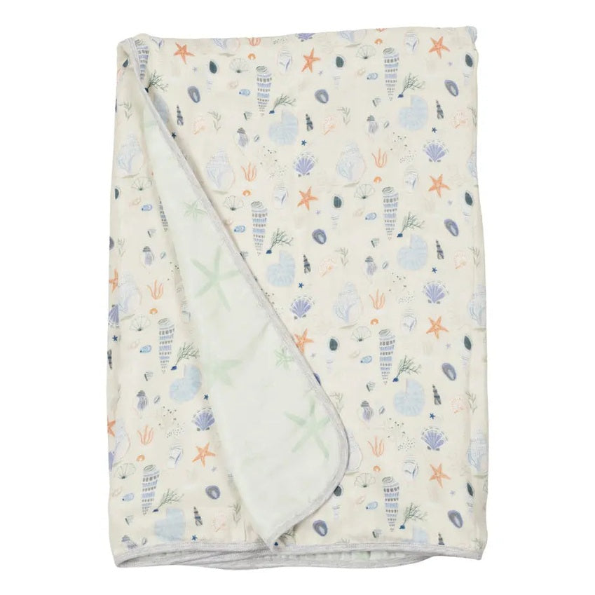 Loulou Lollipop Muslin Quilt Blanket, cream with seashells and starfish, partially folded to reveal soft reverse.