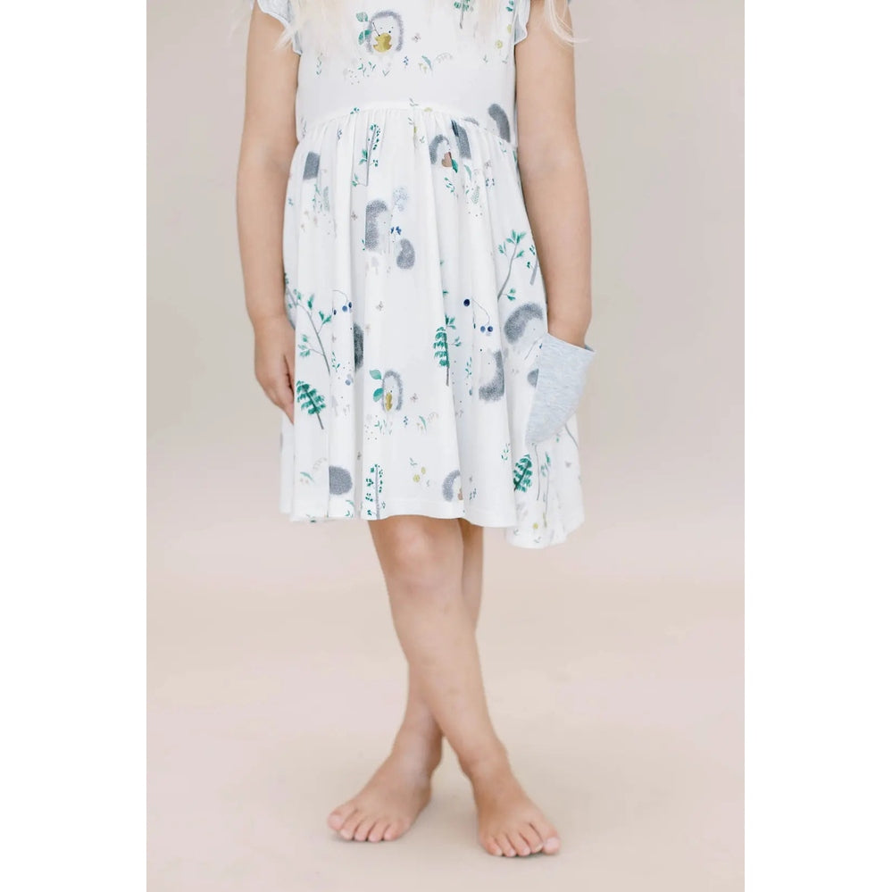 Loulou Lollipop Hedgehogs ruffle pocket dress in white; child stands barefoot with hand in a side pocket.