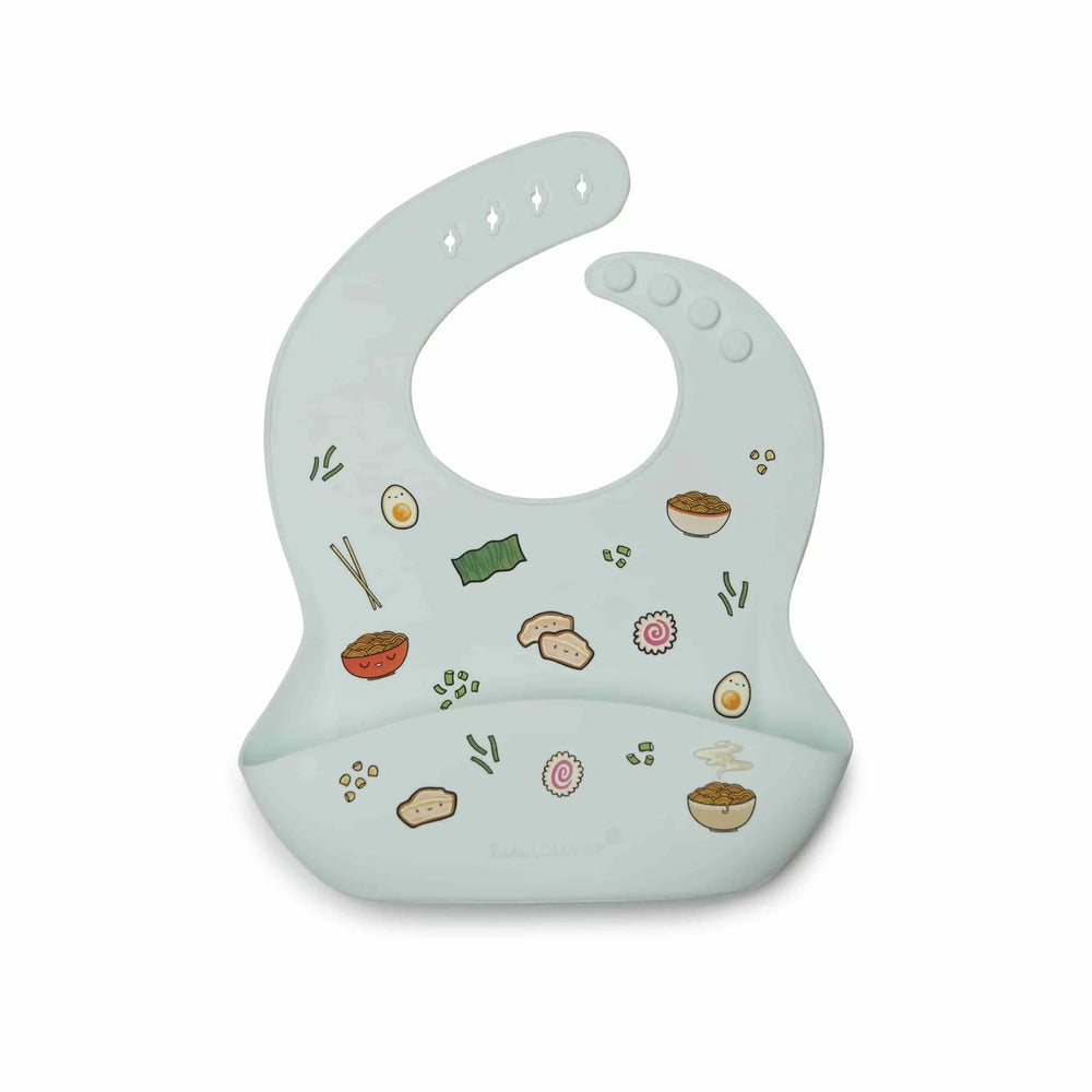 Loulou Lollipop Silicone Bib in pale blue with playful food illustrations; built-in pocket catches crumbs during feeding.