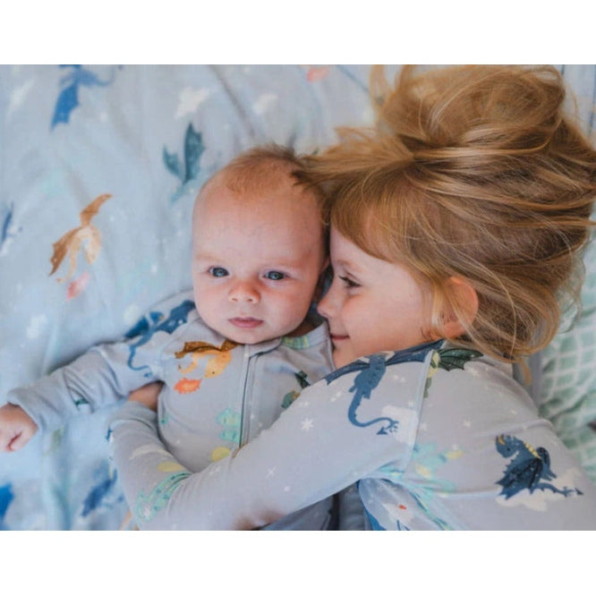 LOULOU LOLLIPOP Sleeper Magical Dragons: a young girl cuddles a baby in matching gray dragon-print sleepwear.