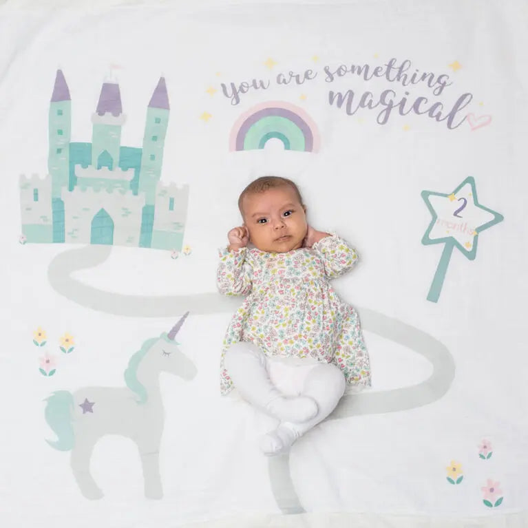 Lulujo Baby's 1St Year Set on pastel unicorn castle blanket with rainbow and stars, baby lying peacefully.