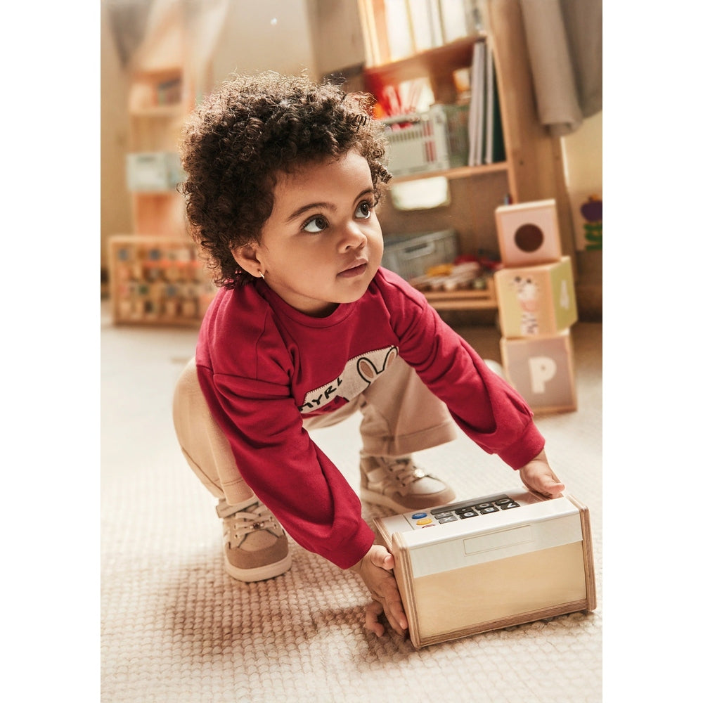 Mayoral Baby Pants and Sweater Set Red, toddler girl in red top and beige pants crouches to lift a wooden toy box.