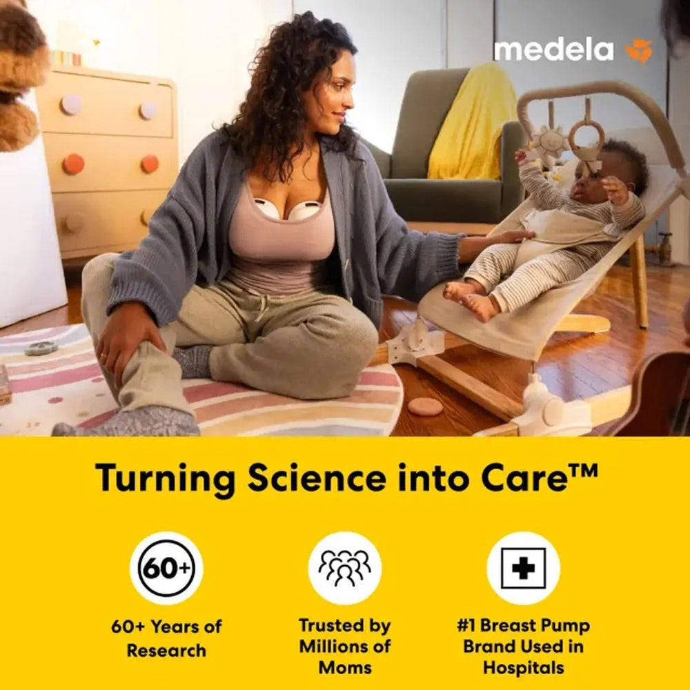 Medela Melody InBra Double Electric Breast Pump in hands-free mode; mom sits cross-legged with baby nearby.